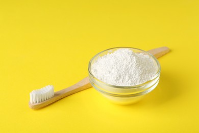 Bowl of tooth powder and brush on yellow background