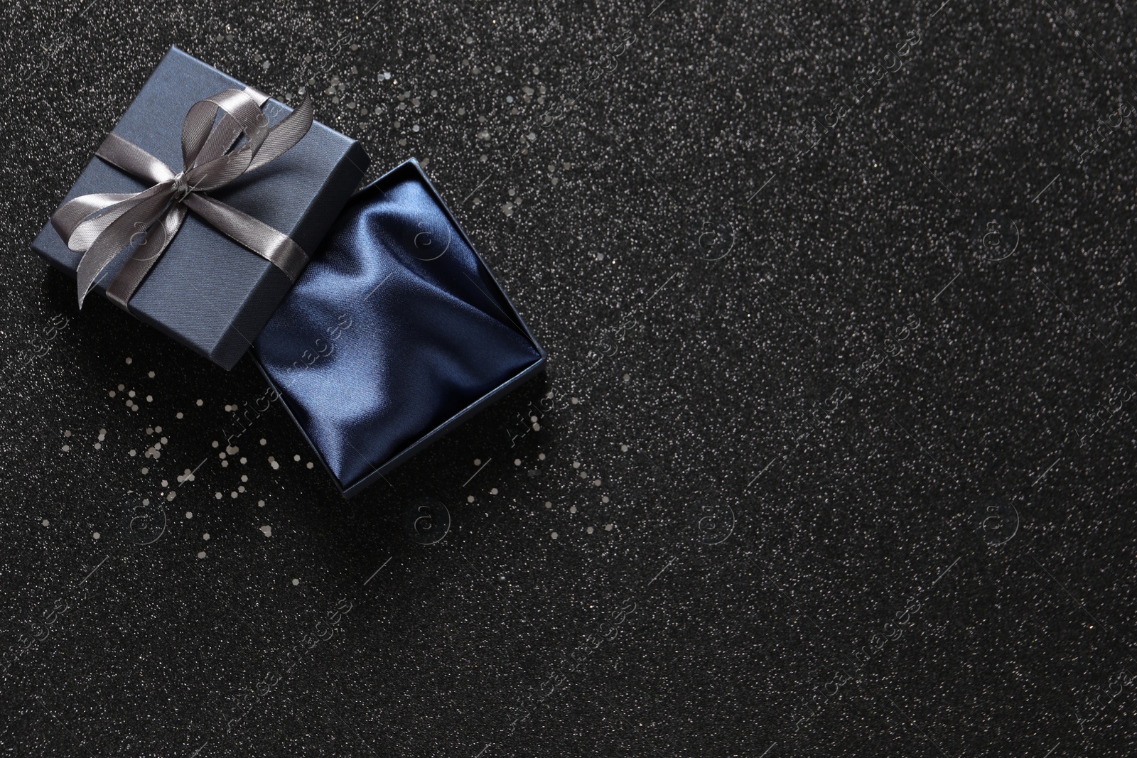 Photo of Open gift box on dark background, top view. Space for text