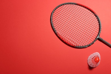 Photo of Badminton racket and shuttlecock on red background, flat lay. Space for text