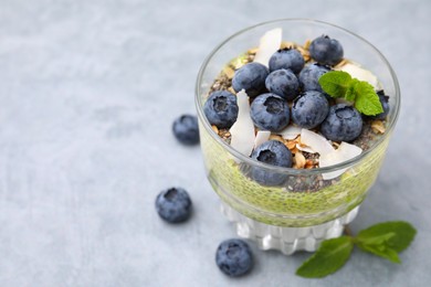Photo of Tasty chia matcha pudding with coconut and blueberries on grey table, space for text. Healthy breakfast