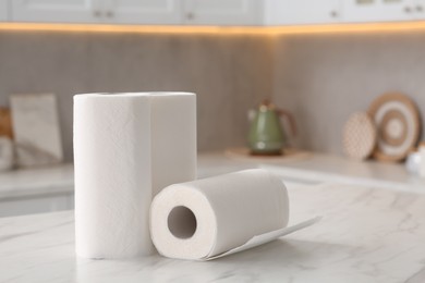 Photo of Rolls of paper towels on white marble table in kitchen. Space for text