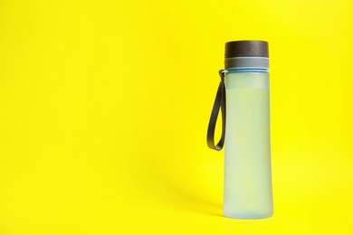 Photo of Stylish closed bottle with water drops on yellow background, space for text