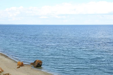 Picturesque view of sandy beach with stones and beautiful sea