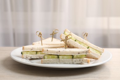 Photo of Tasty sandwiches with cream cheese and cucumber served on white wooden table