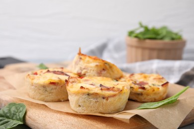 Photo of Delicious egg muffins with cheese and bacon on wooden board, closeup. Space for text