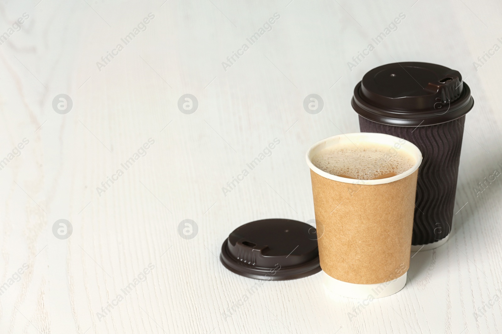 Photo of Cardboard cups of coffee on wooden background. Space for text