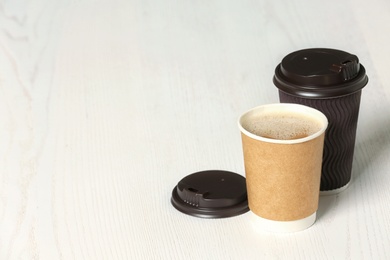 Cardboard cups of coffee on wooden background. Space for text