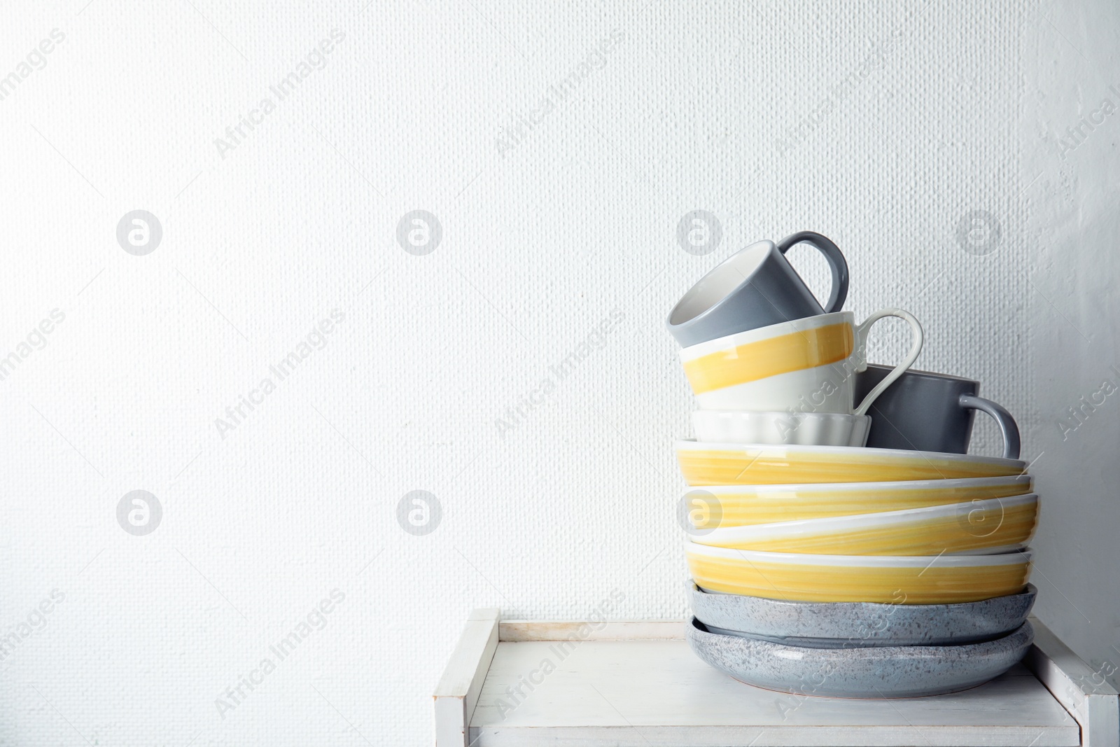 Photo of Set of dinnerware on table against light background with space for text. Interior element