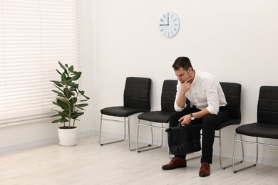 Photo of Man sitting on chair and waiting for job interview indoors