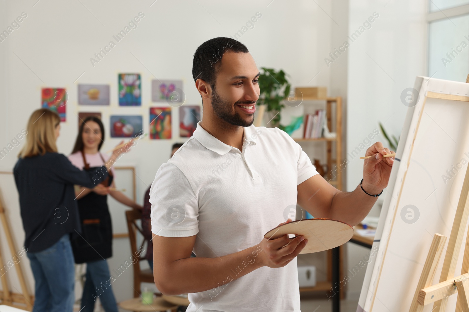 Photo of Group of students attending painting class in studio. Creative hobby