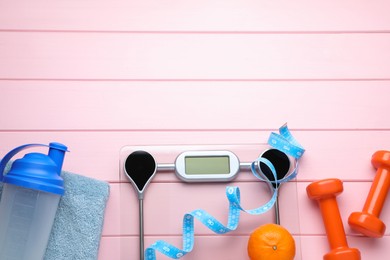 Photo of Flat lay composition with bathroom scale and measuring tape on pink wooden floor , space for text. Weight loss concept