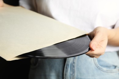 Woman taking vinyl record out of paper sleeve, closeup