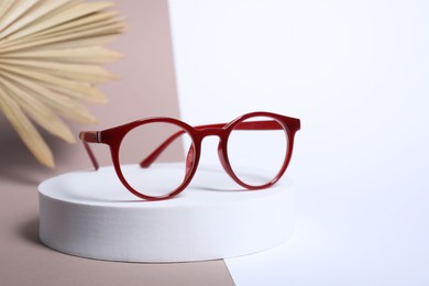 Photo of Stylish presentation of glasses with red frame on color background