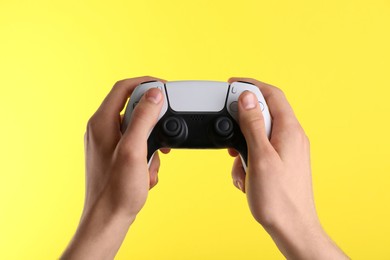 Photo of Man using wireless game controller on yellow background, closeup