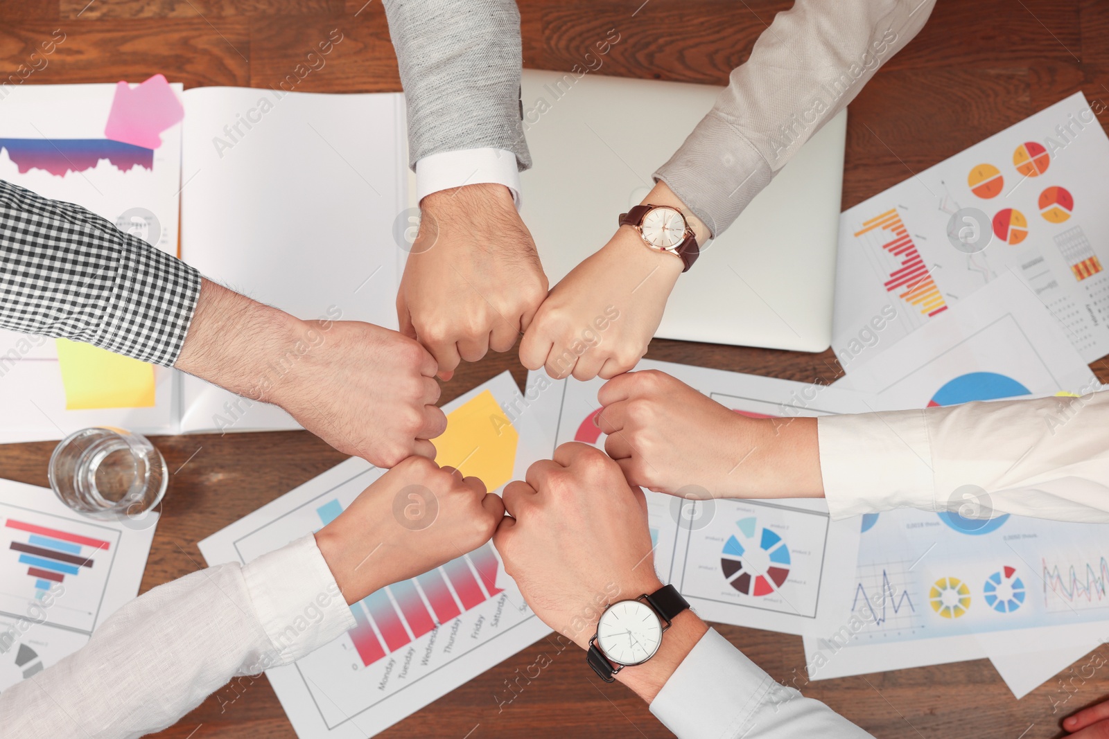 Photo of Office employees joining hands at work, top view