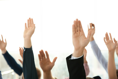 Photo of People raising hands to ask questions at business training on light background, closeup