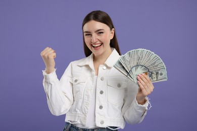 Photo of Excited woman with dollar banknotes on purple background