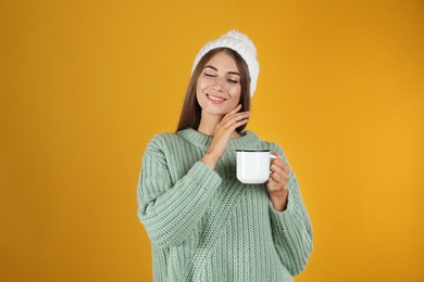 Photo of Happy beautiful woman with mug of mulled wine on yellow background