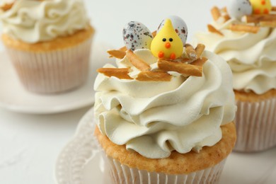 Photo of Tasty Easter cupcakes with vanilla cream on white table, closeup