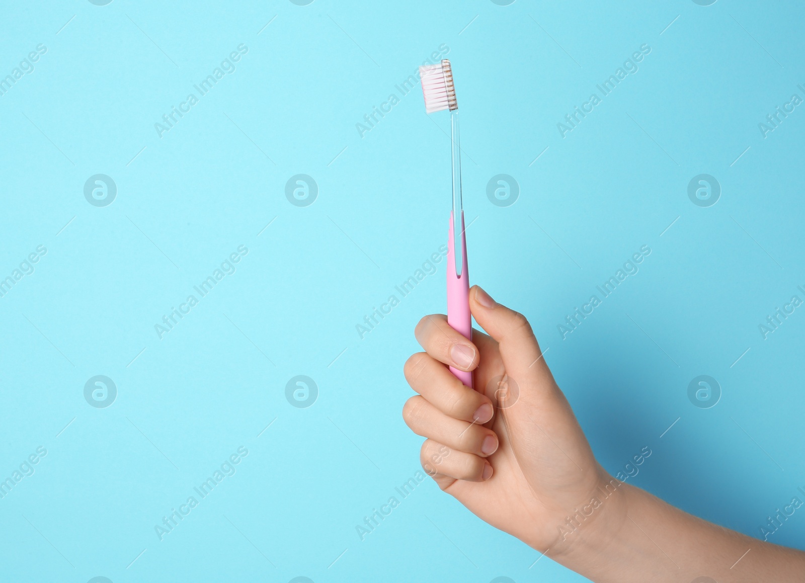 Photo of Woman holding manual toothbrush against color background