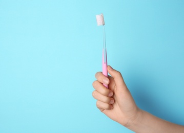 Photo of Woman holding manual toothbrush against color background