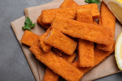 Photo of Fresh breaded fish fingers served on grey table, top view