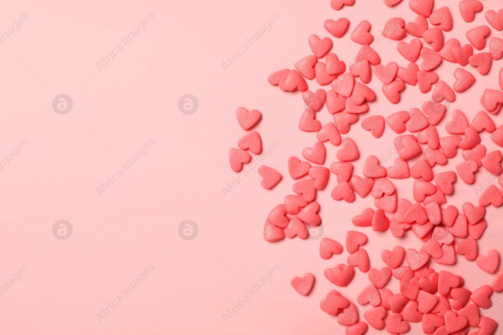 Photo of Heart shaped sprinkles on pink wooden table, flat lay. Space for text