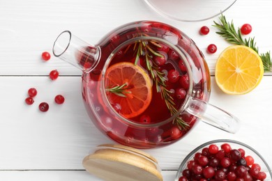 Tasty hot cranberry tea with lemon, rosemary and fresh berries on white wooden table