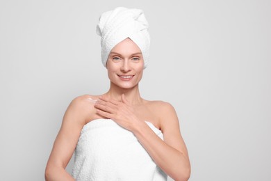 Photo of Woman applying body cream onto her collarbone against white background, space for text