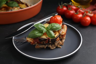 Photo of Plate of delicious eggplant lasagna served on black table, closeup