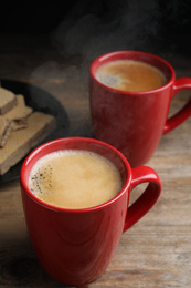 Photo of Delicious coffee and wafers on wooden table