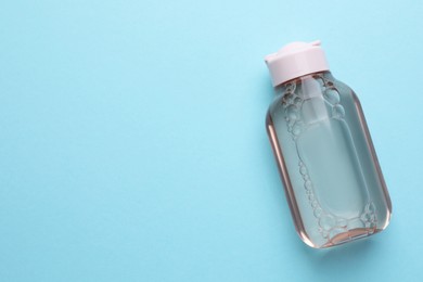 Photo of Micellar water on light blue background, top view. Space for text
