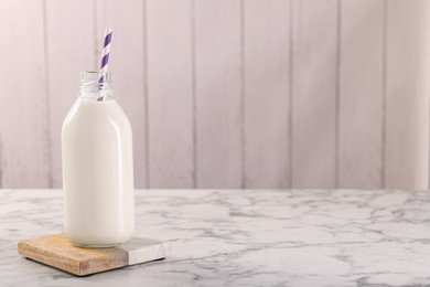 Photo of Bottle of tasty milk on white marble table, space for text