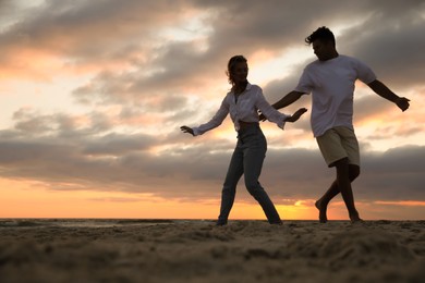 Photo of Happy couple dancing on beach at sunset