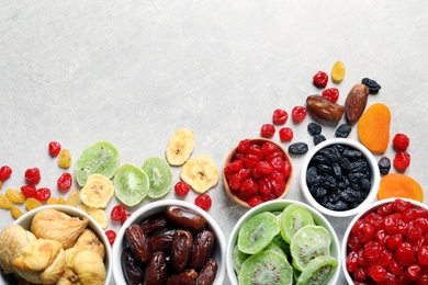 Photo of Bowls of different dried fruits on grey background, top view with space for text. Healthy food