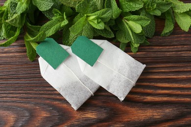 Photo of Tea bags and mint on wooden table, top view