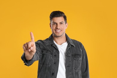 Photo of Man showing number one with his hand on yellow background