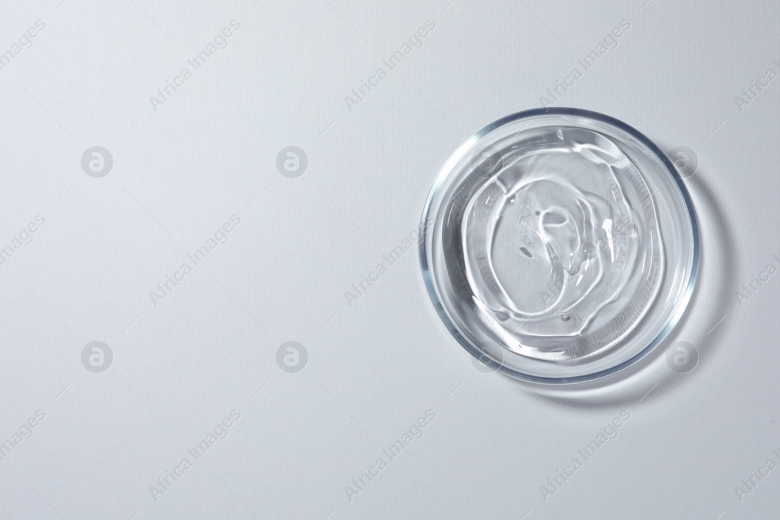 Photo of Petri dish with liquid on white background, top view. Space for text