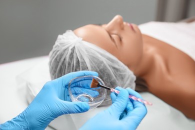 Photo of Cosmetologist with bowl and brush in salon. Peeling procedure