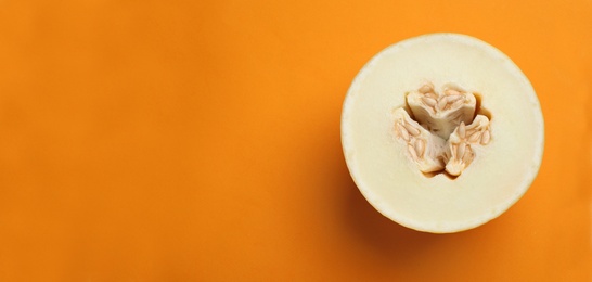 Photo of Half of ripe tasty melon on orange background, top view. Space for text