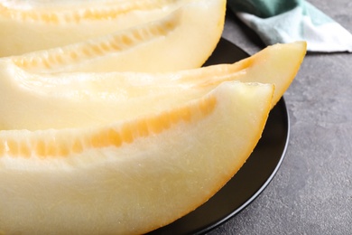 Photo of Slices of delicious honey melon on black table, closeup