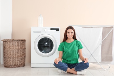 Young woman near washing machine at home. Laundry day