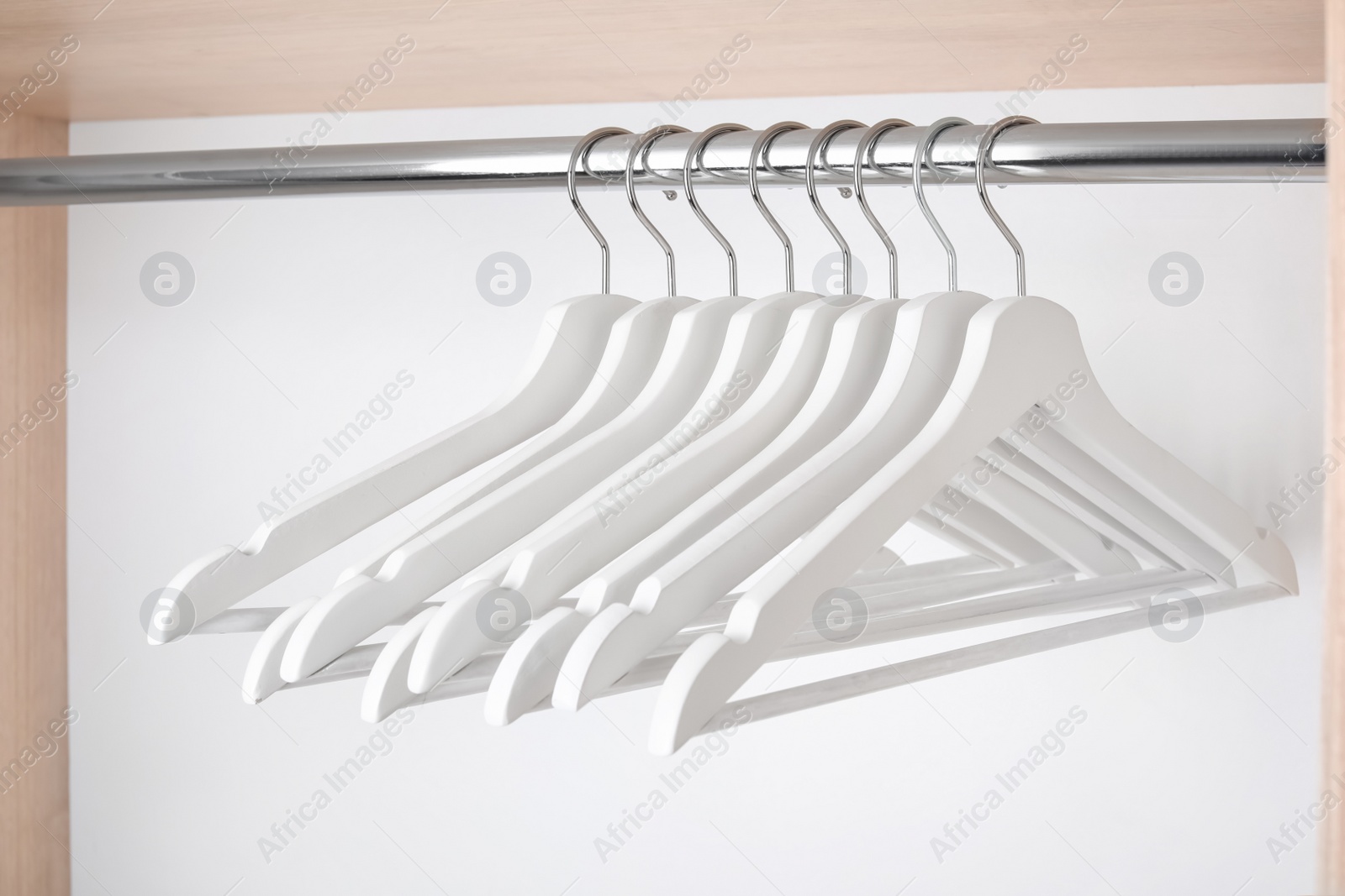 Photo of Clothes hangers on metal rail in wardrobe