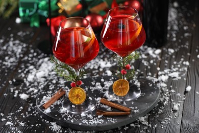 Photo of Christmas Sangria cocktail in glasses and snow on dark wooden table