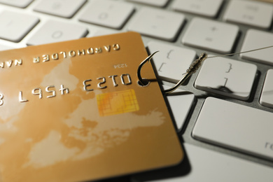 Photo of Hook with credit card on computer keyboard, closeup. Cyber crime concept