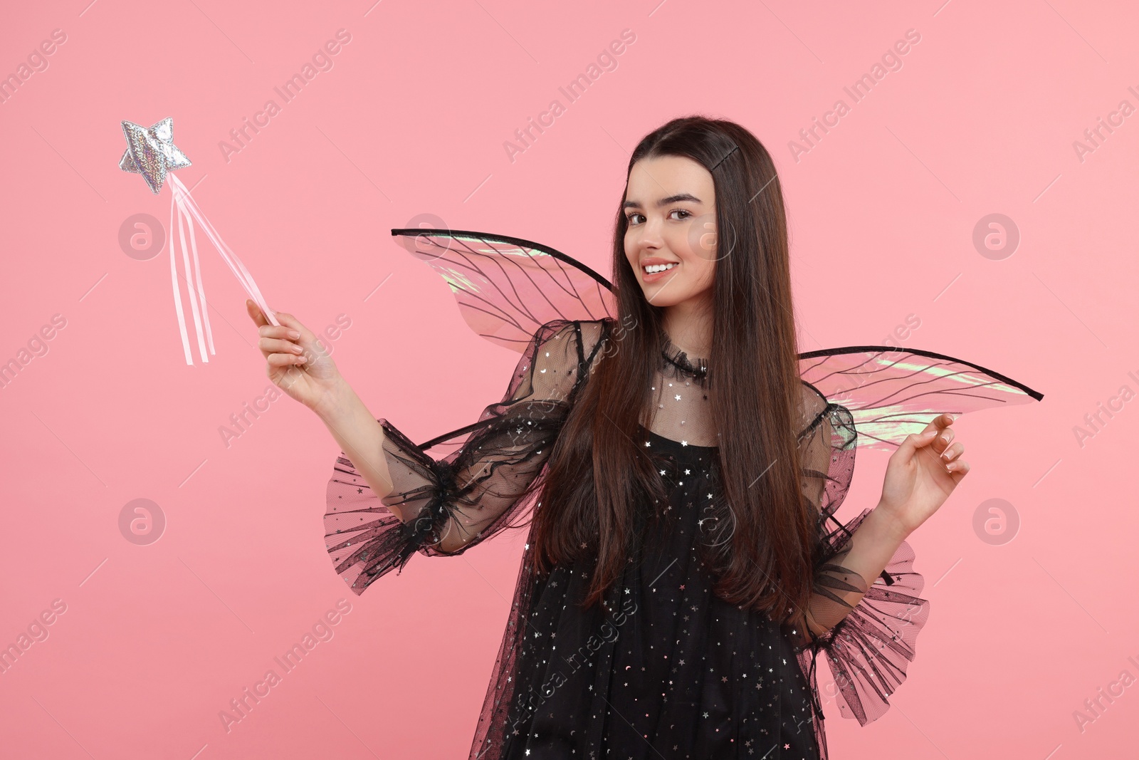 Photo of Beautiful girl in fairy costume with wings and magic wand on pink background