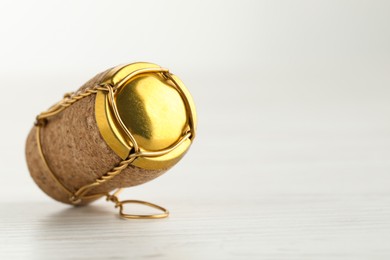 Photo of Cork of sparkling wine and muselet cap on white wooden table, closeup. Space for text