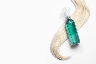 Photo of Spray bottle with thermal protection and lockblonde hair on white background, flat lay. Space for text