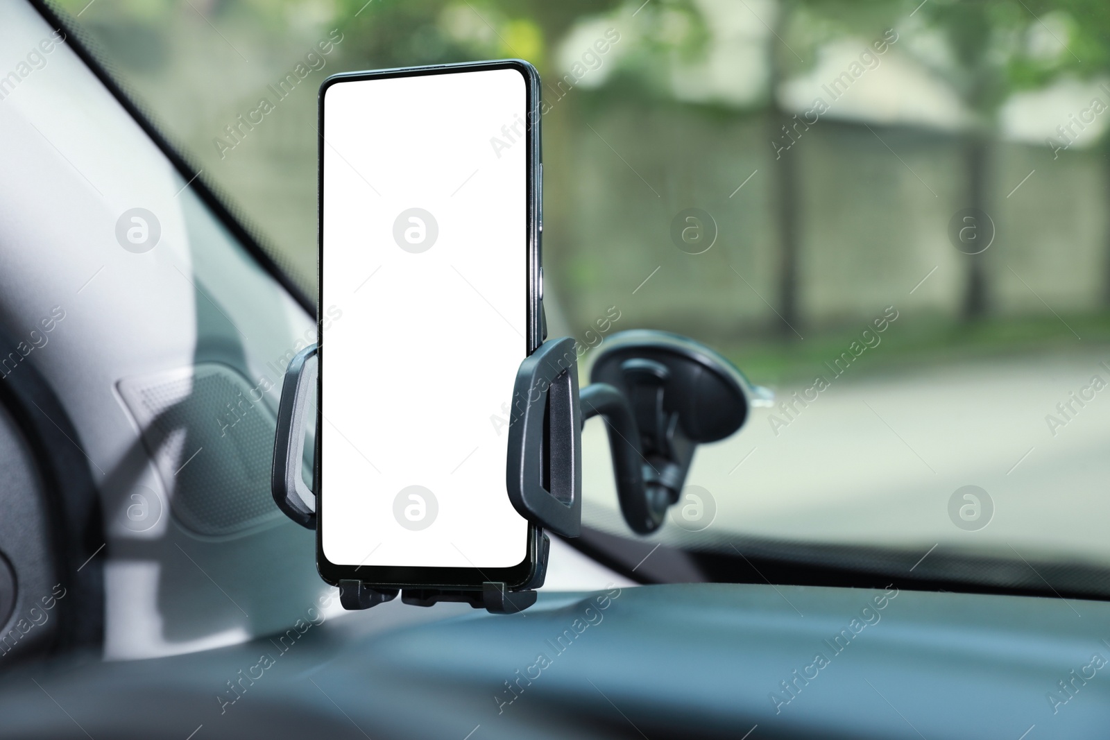 Photo of Car holder with modern mobile phone on windshield of automobile. Mockup for design