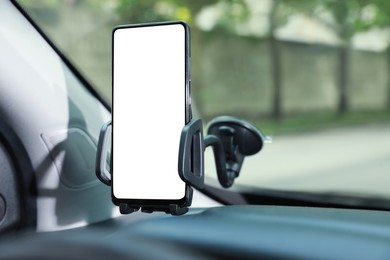 Photo of Car holder with modern mobile phone on windshield of automobile. Mockup for design